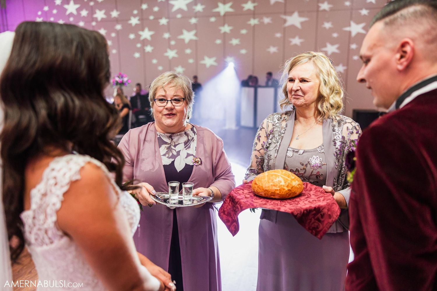 Wedding reception guests presenting traditional bread on platters with decorative stars in background.
