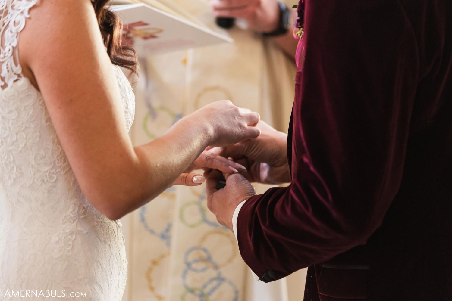 Close-up shot of hands exchanging wedding rings during church ceremony.