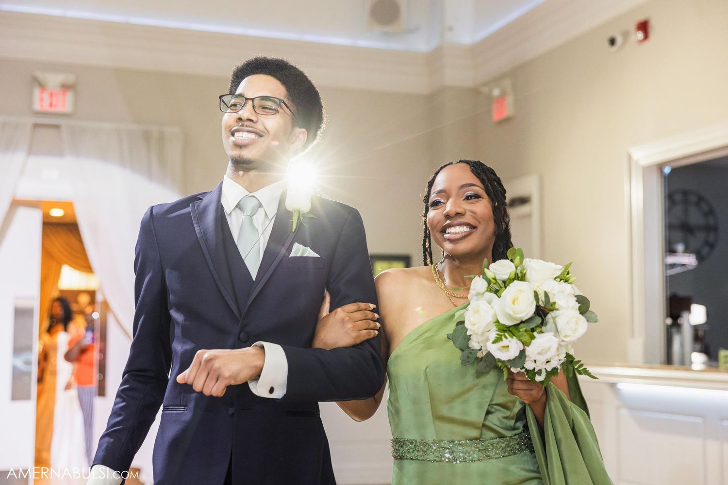 Formal wedding party members walking arm in arm during ceremony procession.