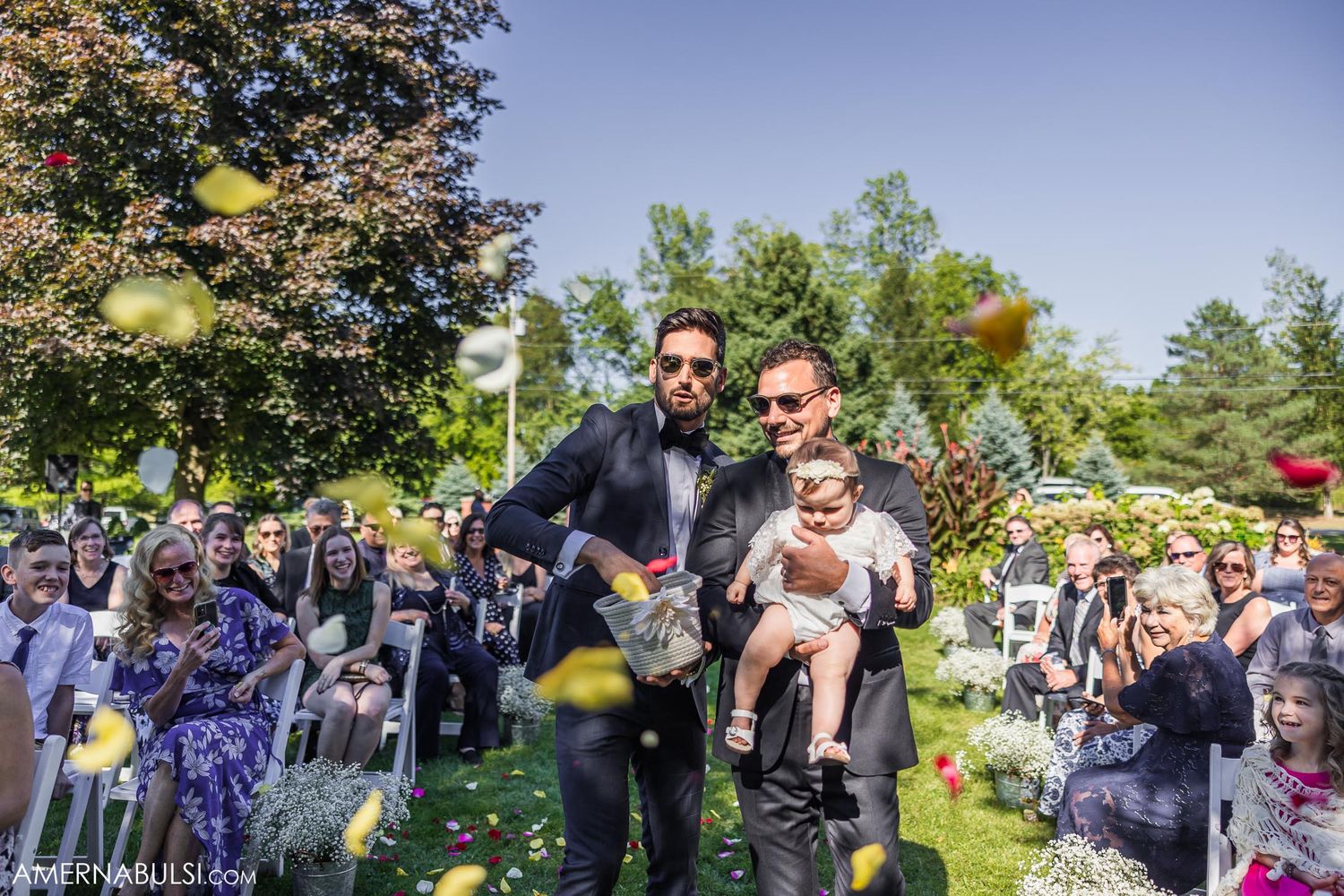 Wedding celebration in a sunny outdoor garden setting with bubbles floating through the air.