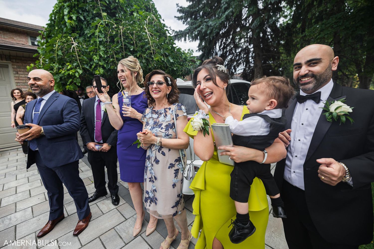 Wedding guests gather outside venue in colorful formal attire during celebration.