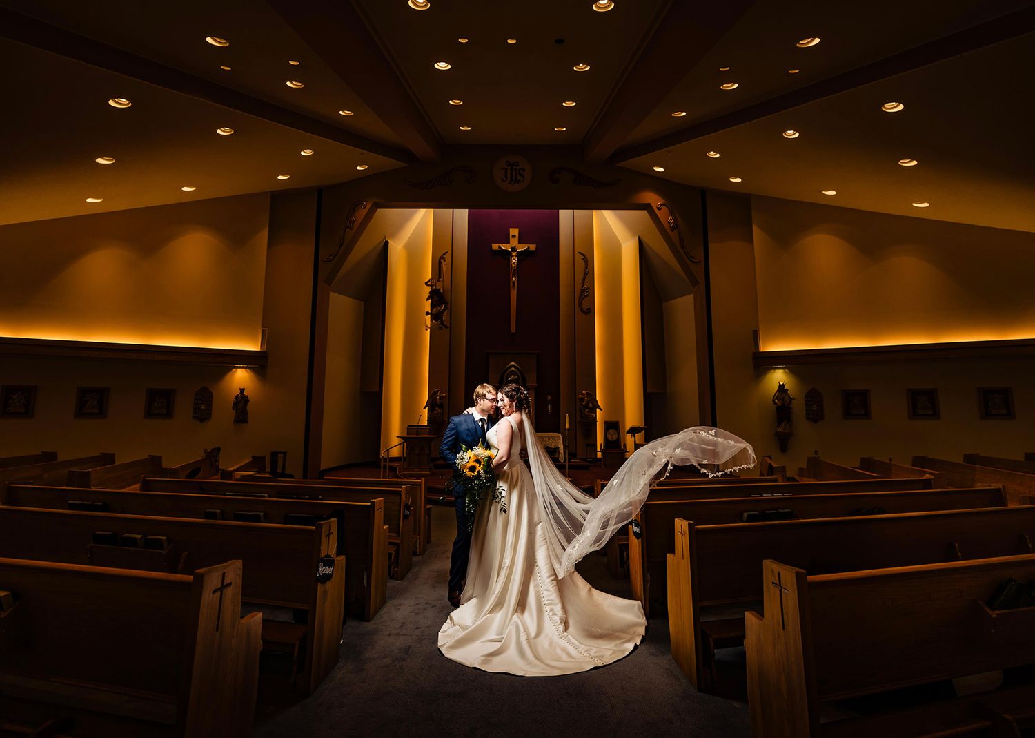 Dramatic silhouette of a couple dancing in a dimly lit church sanctuary.