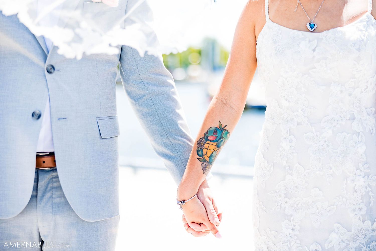 Close-up of couple's hands showing tattoo art and formal wedding attire.