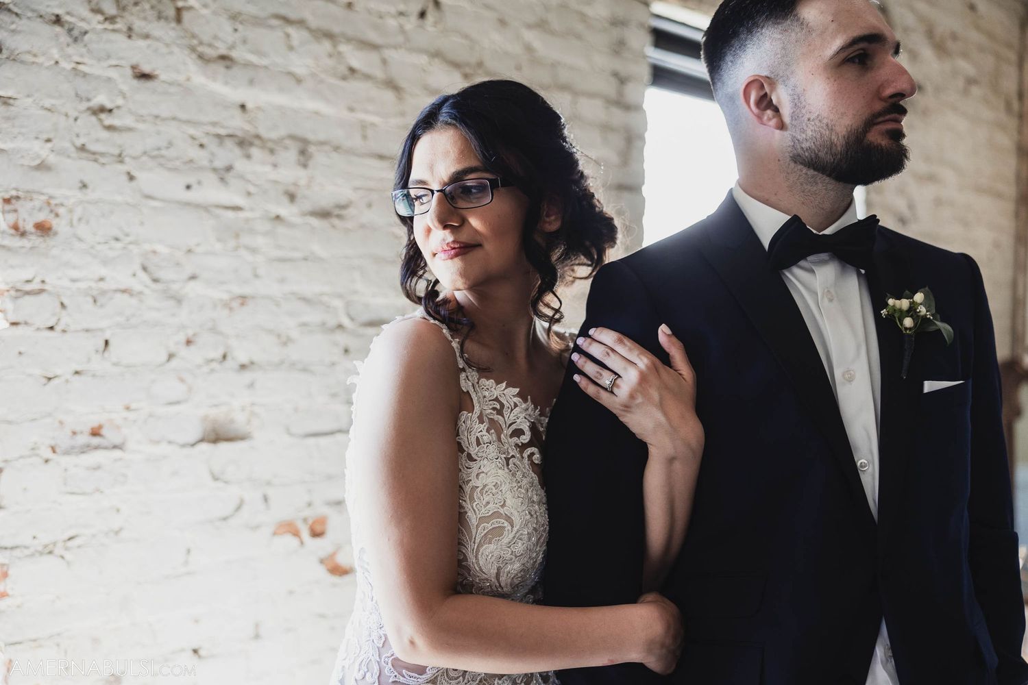 An intimate moment captured between newlyweds against a white brick wall backdrop.