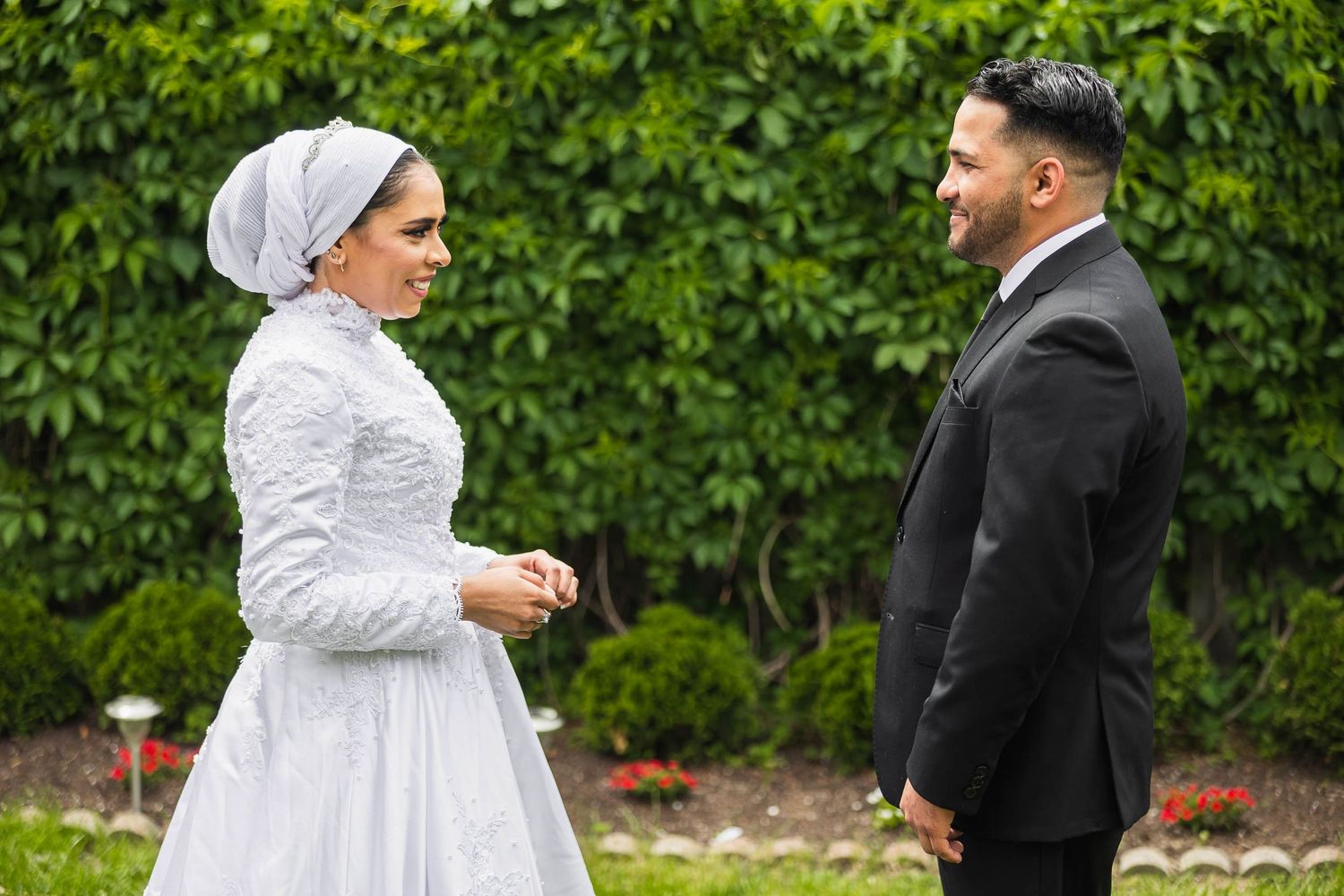 Couple sharing a moment during their wedding ceremony against lush garden backdrop.