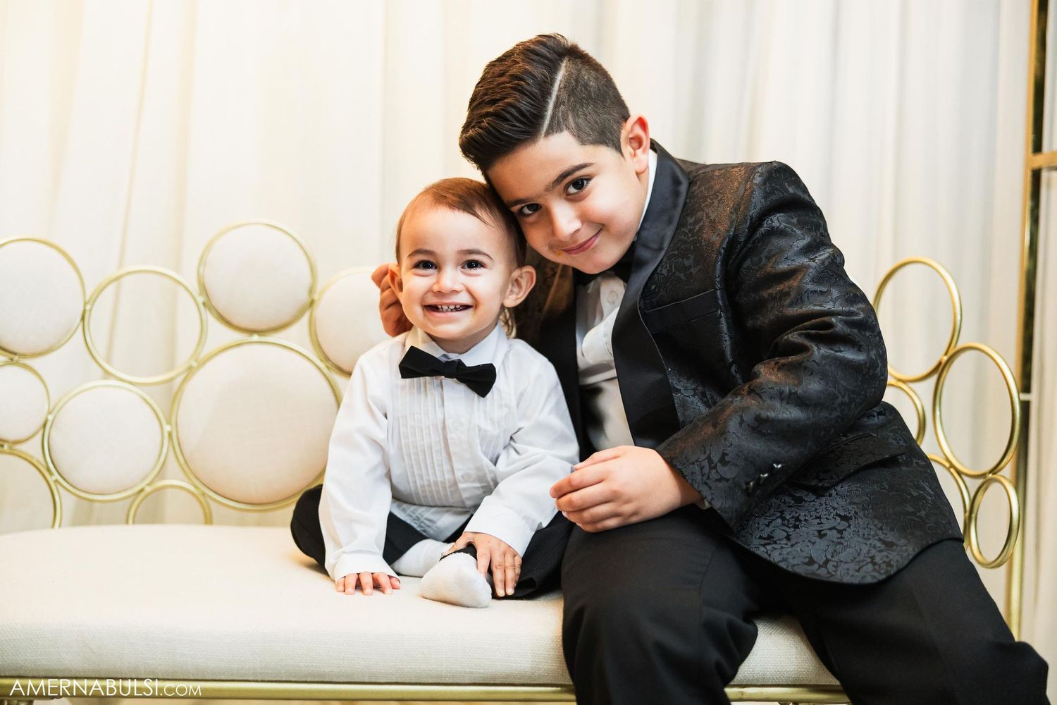 A formal portrait featuring a young child and older companion sitting together on an elegant white couch.