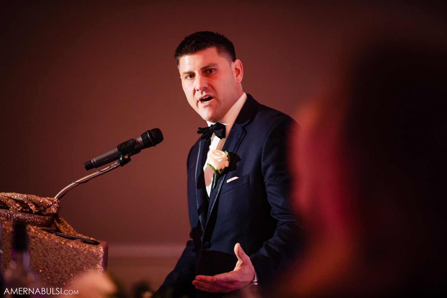 Wedding band performers sing and entertain guests during an elegant reception with dramatic red lighting.