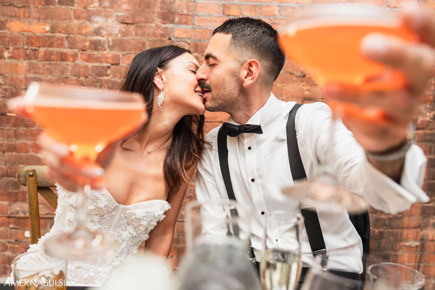 Wedding celebration with champagne toasts against exposed brick wall background.