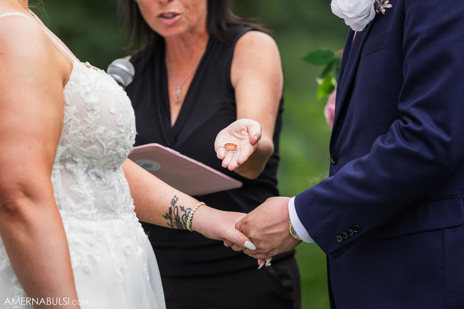 Close-up of hands during ring exchange ceremony with officiant holding ceremony book.