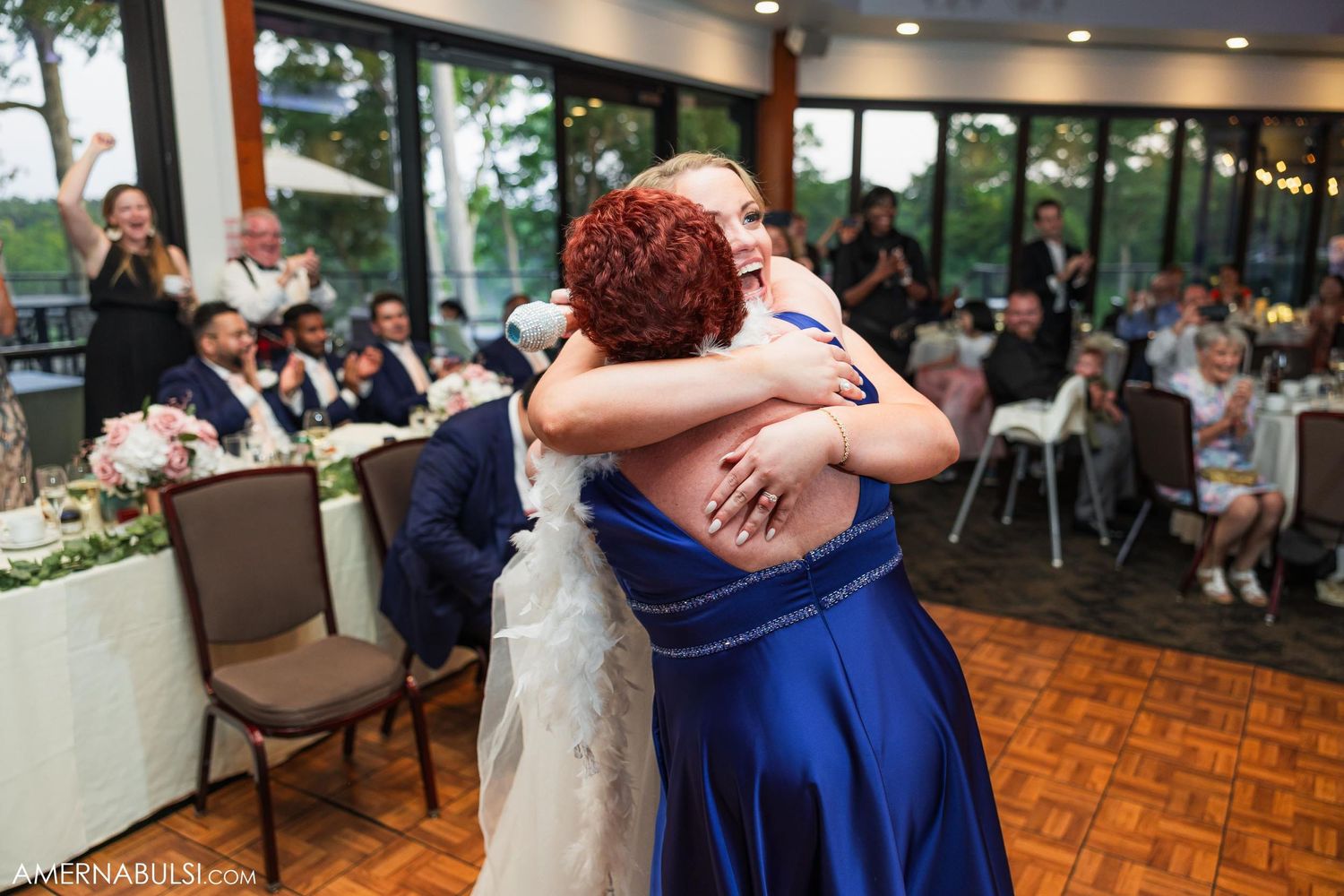 Two guests share an emotional embrace during wedding reception on parquet dance floor.