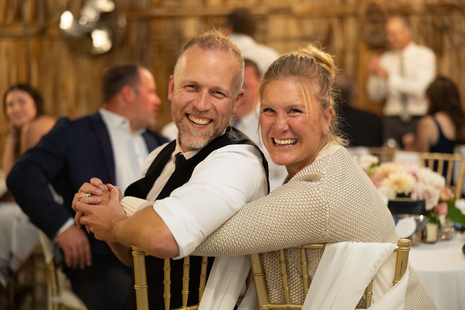 Wedding guests enjoying themselves during a festive reception in a rustic barn-style venue.