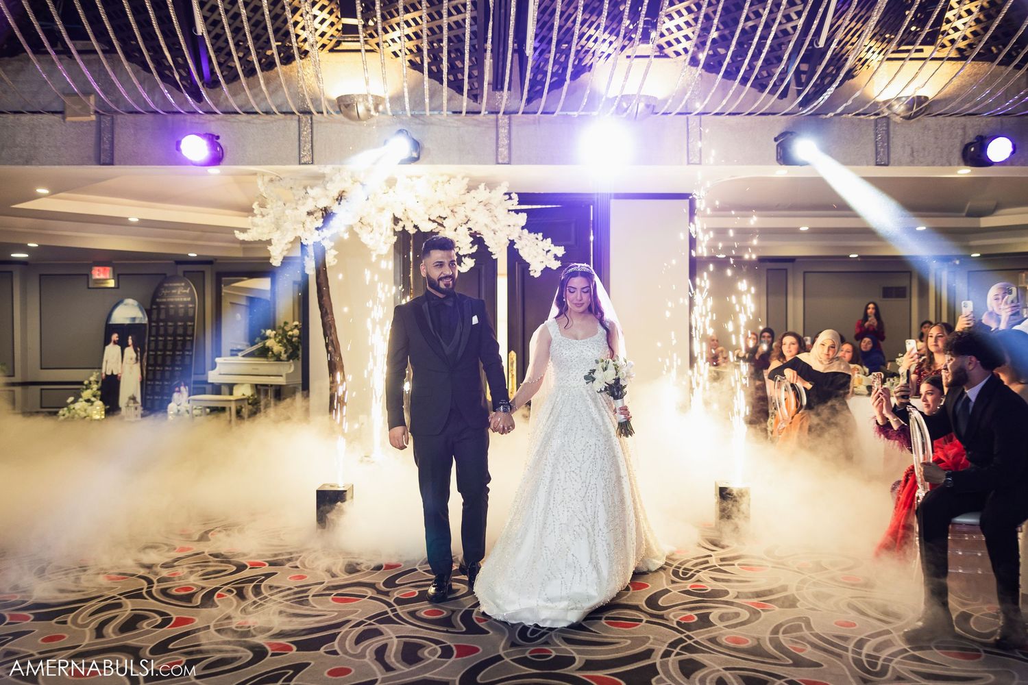 A couple makes their grand entrance at a wedding reception with dramatic fog and lighting effects on the dance floor.
