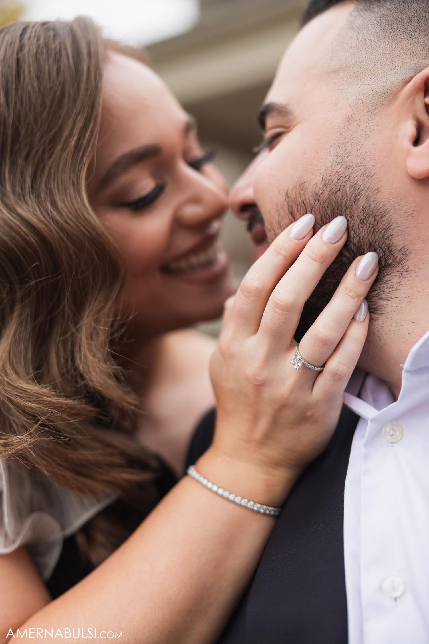 A close-up engagement photo showing affection between a couple with a diamond ring visible.
