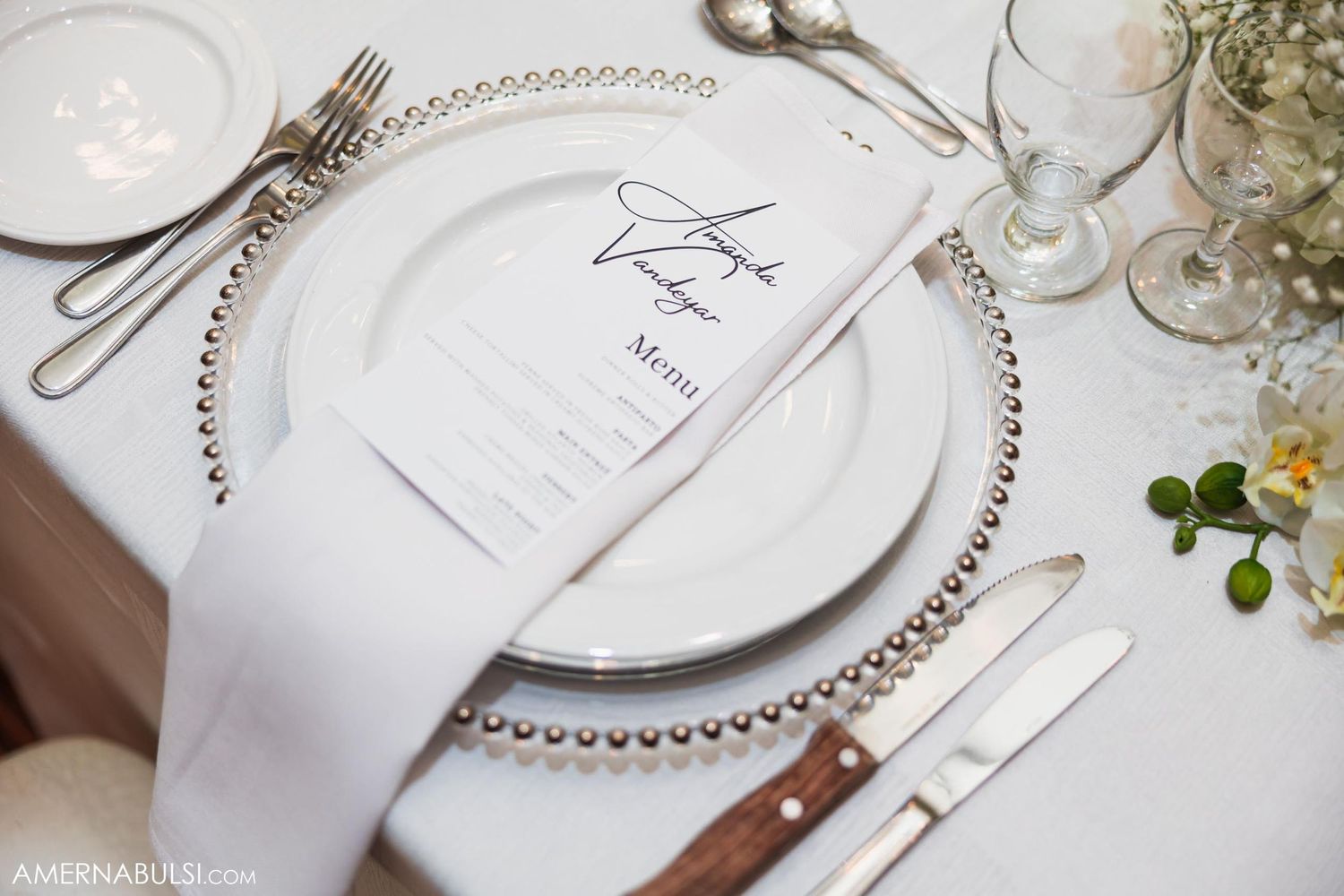 Close-up of elegant place setting with beaded charger plate and wedding menu.