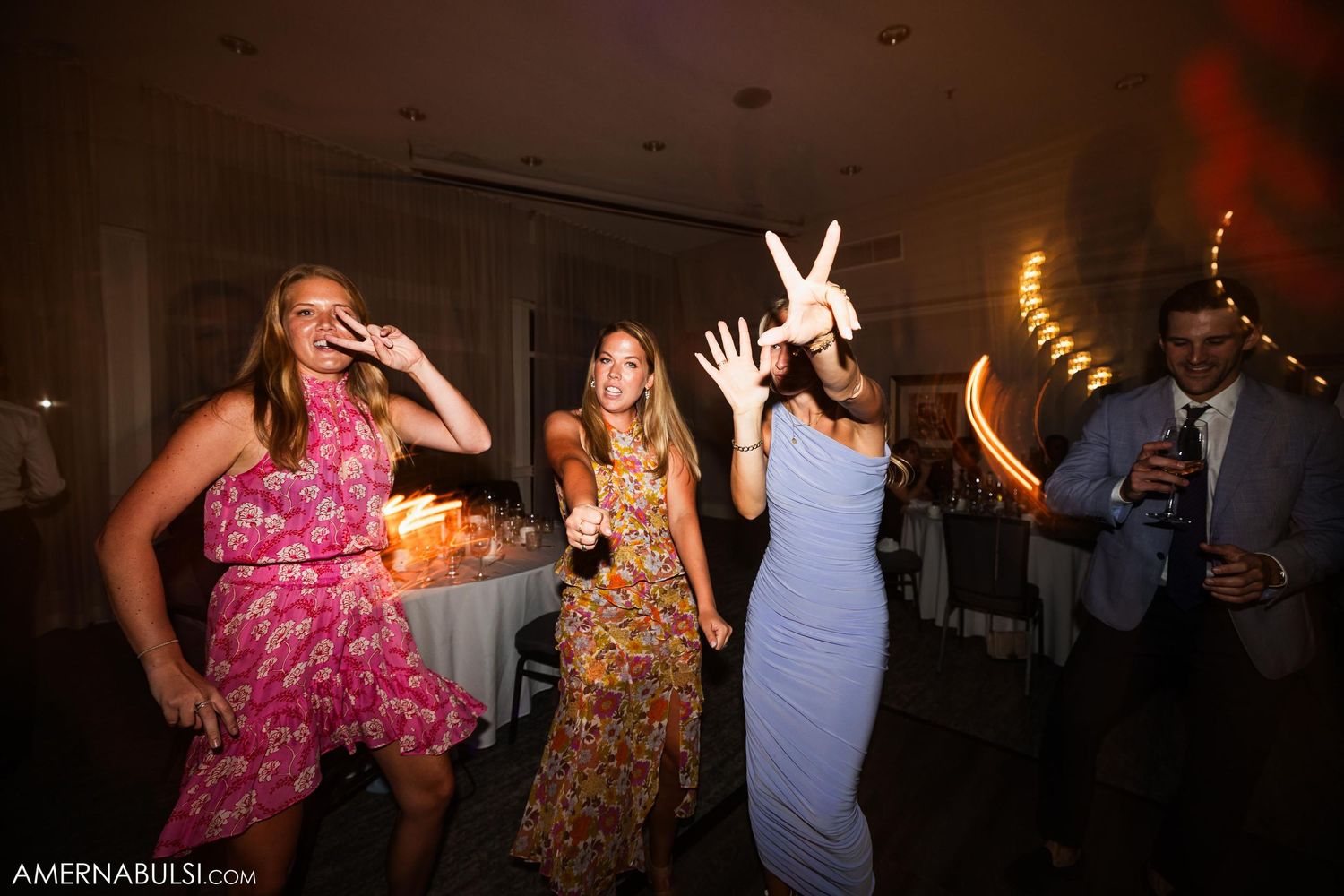 Wedding guests dancing and celebrating enthusiastically at a lively reception party.