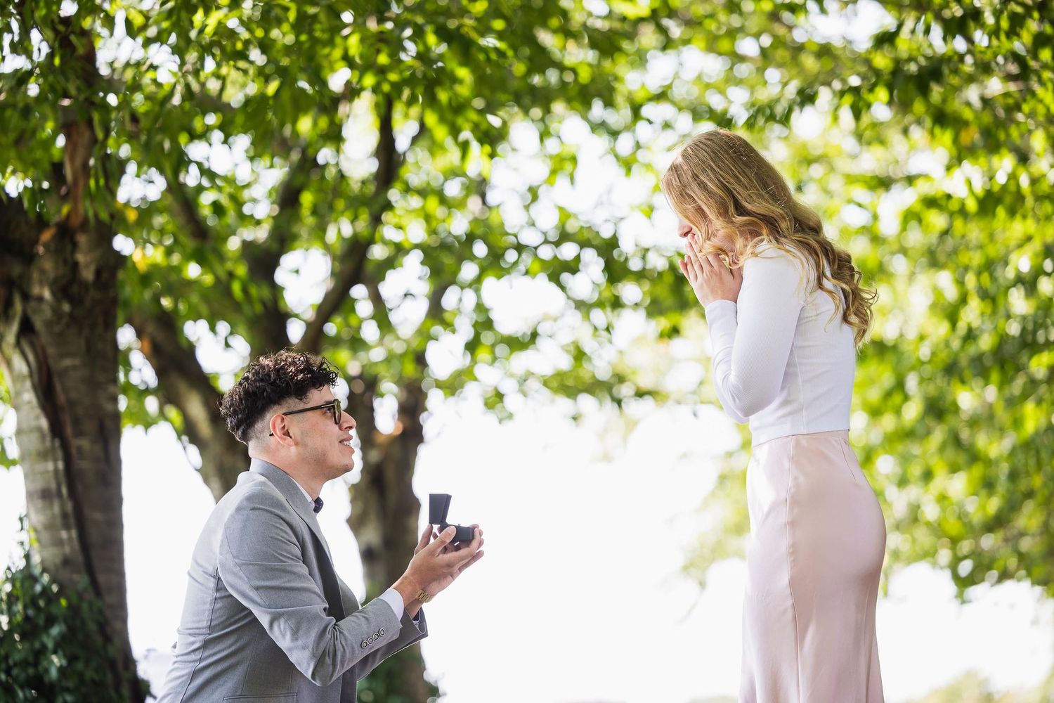 Marriage proposal scene in lush green garden setting.