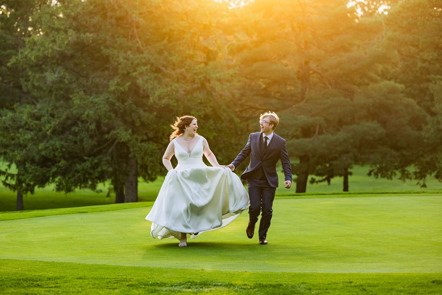 Couple dances on lush green golf course during golden hour sunset.