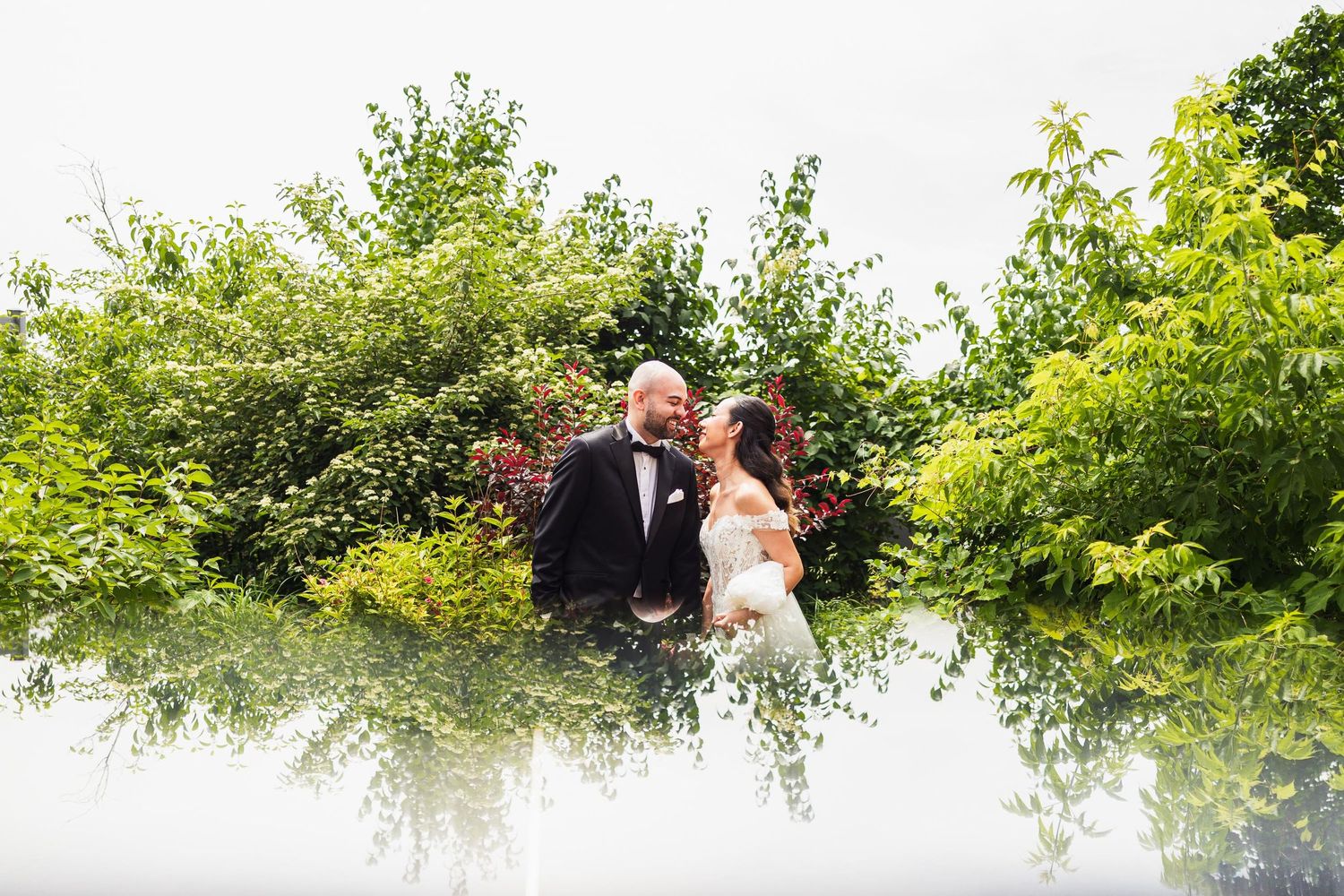 Artistic wedding portrait with couple surrounded by green foliage and creative double exposure effect.