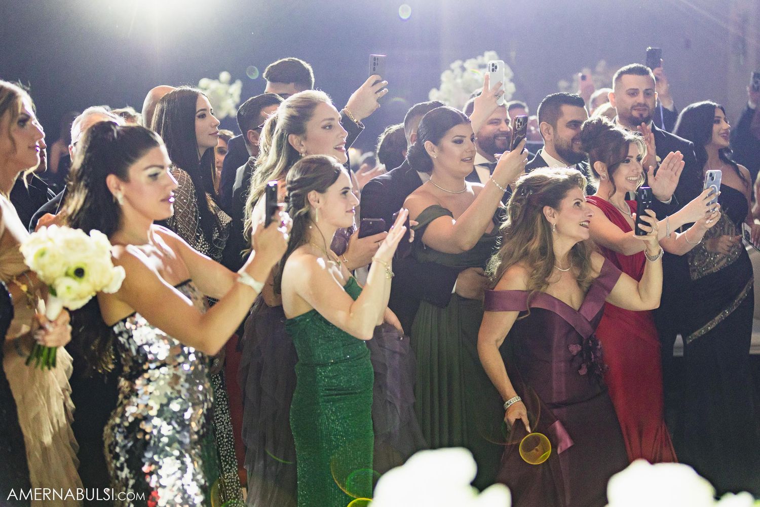 Wedding guests in formal attire dancing and celebrating at reception.