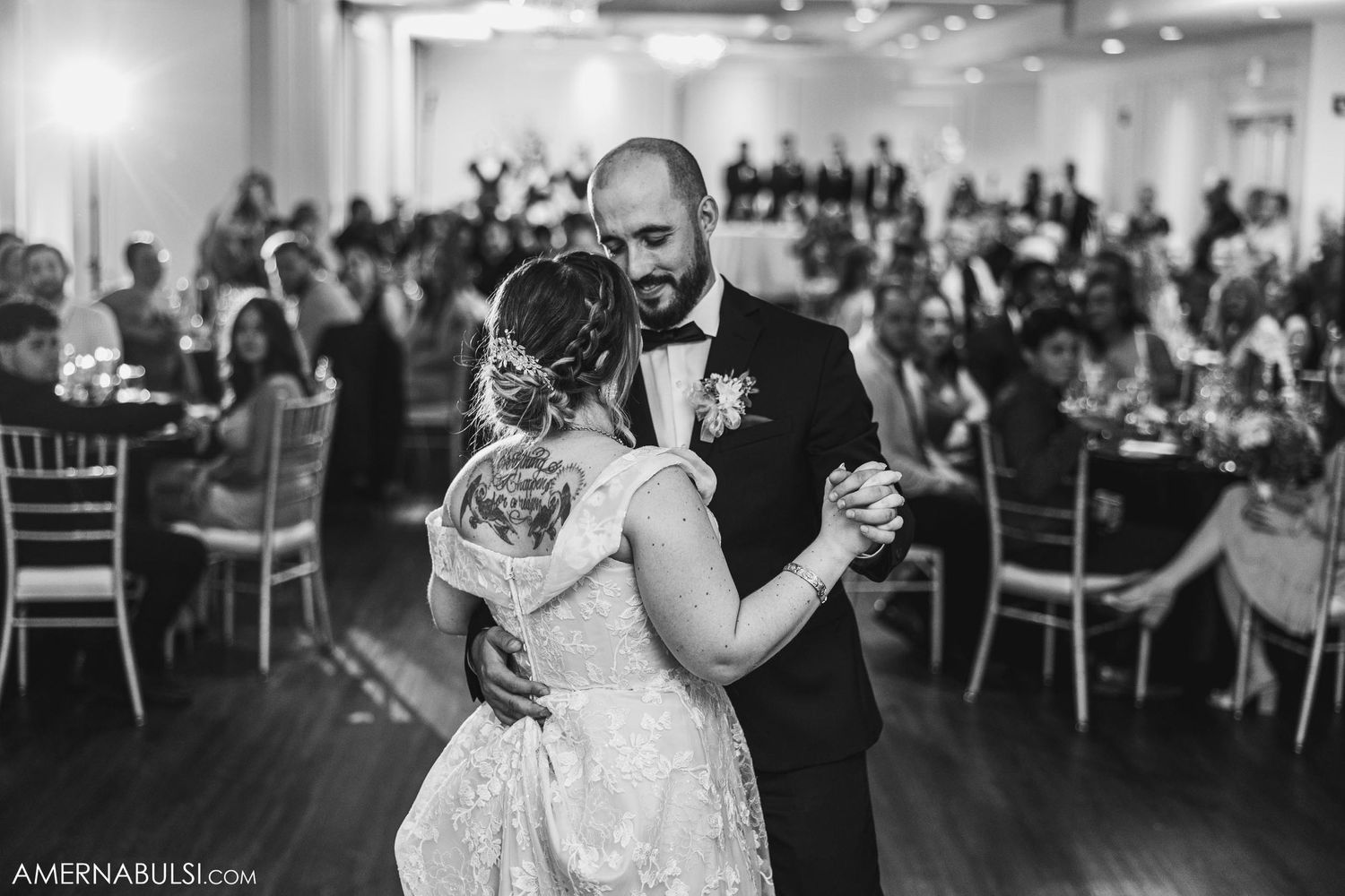 Wedding couple dancing together in elegant reception hall filled with guests.