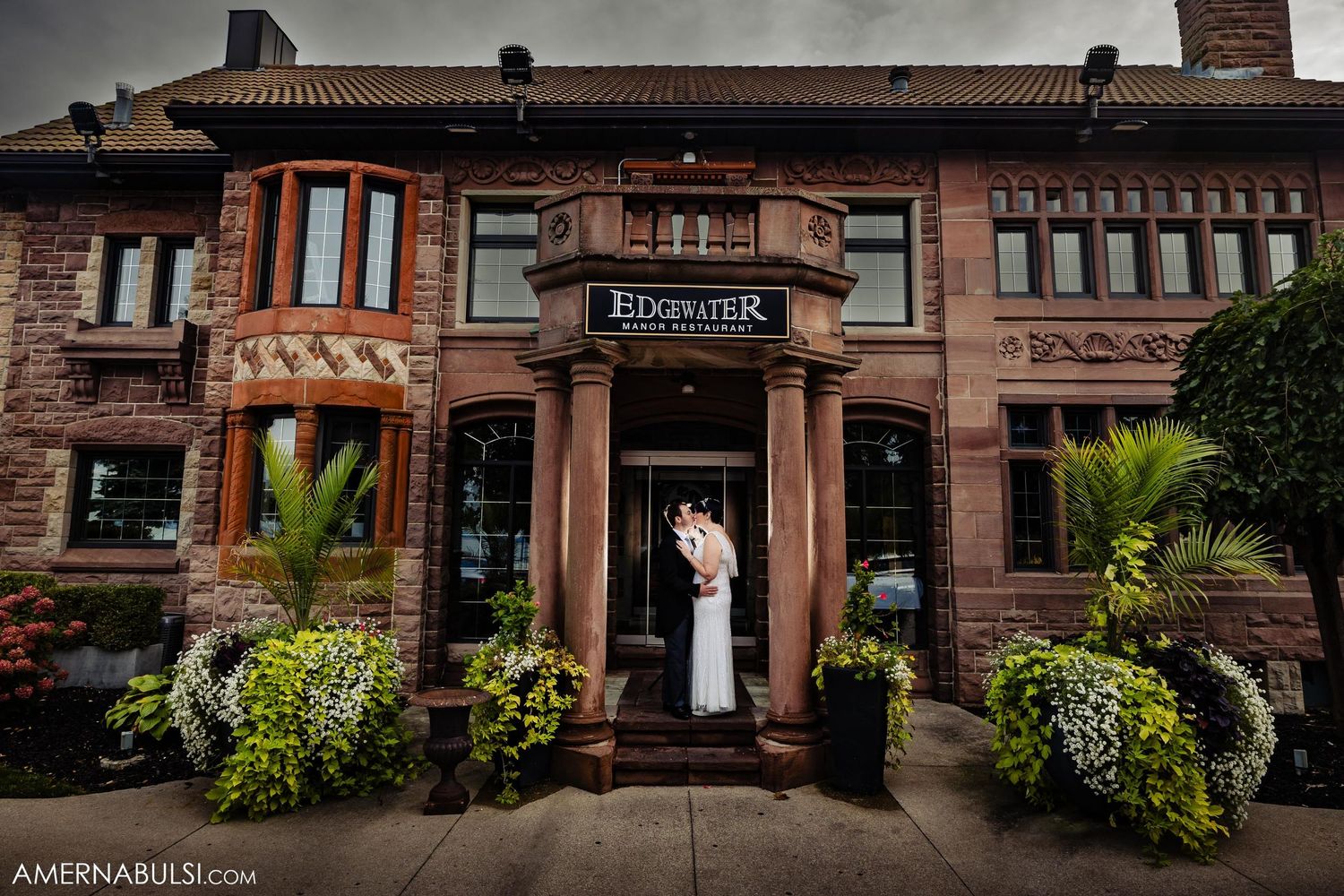 Historic brick Edgewater Manor Restaurant entrance decorated with potted plants and flowers.