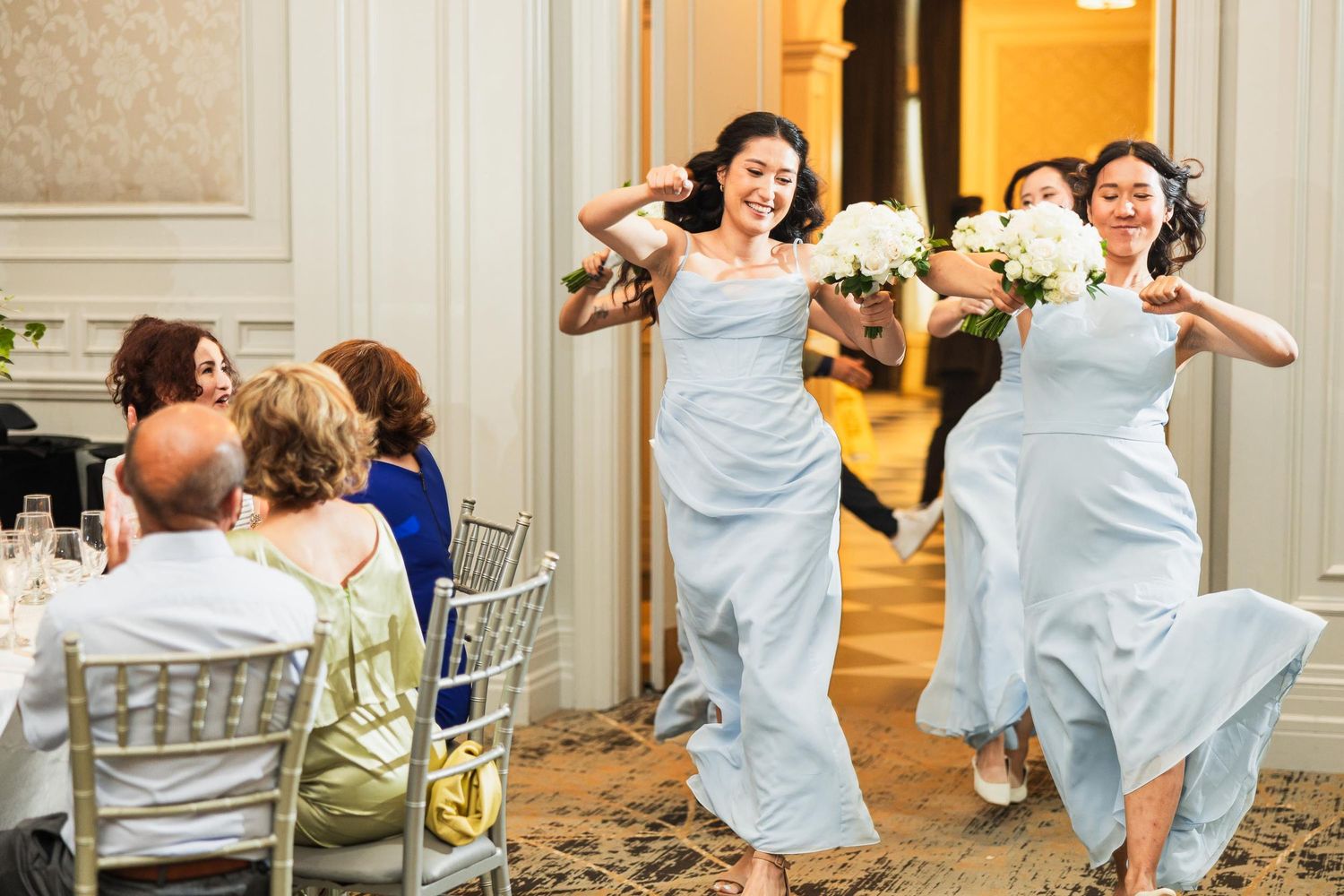 Bridesmaids in matching blue gowns dance energetically at reception.
