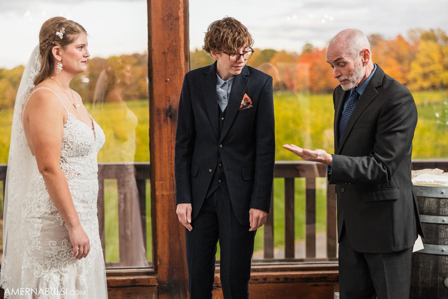 A wedding ceremony in progress on a covered deck with beautiful fall colors in the distance.