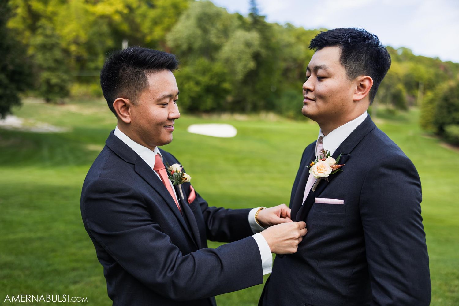Formal moment before wedding ceremony as groomsman adjusts companion's boutonniere.