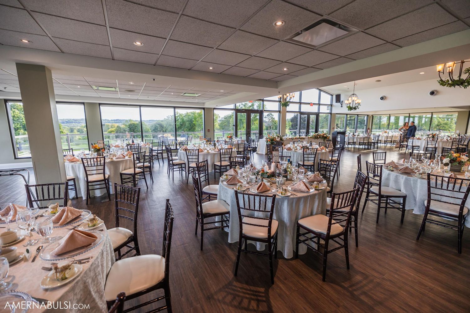 Elegant wedding reception venue with round tables, Chiavari chairs and scenic window views.