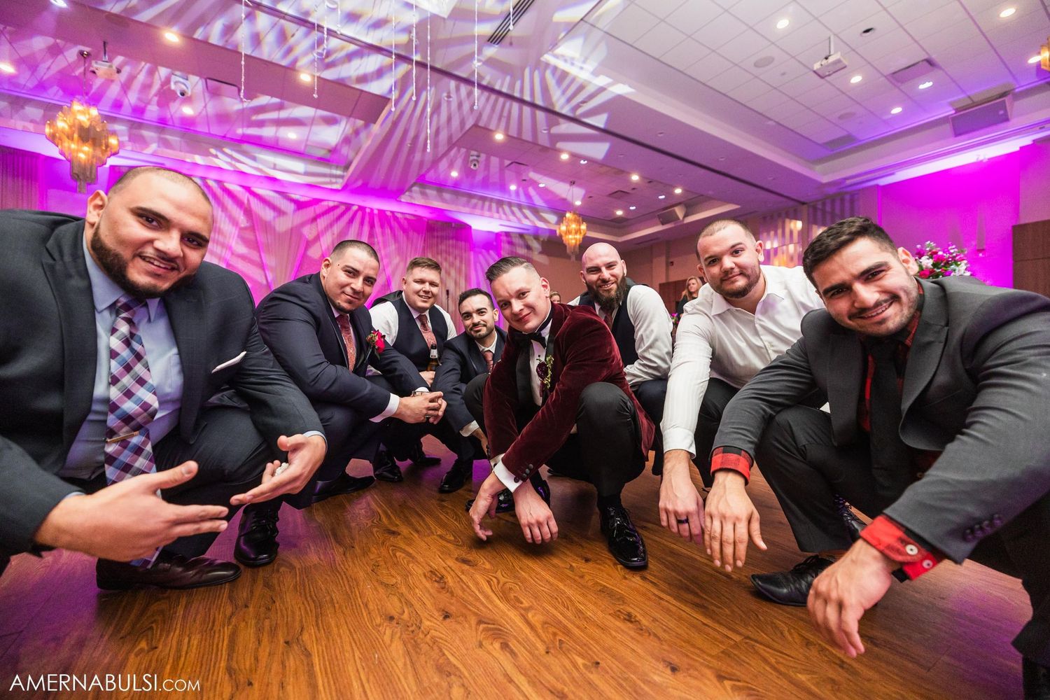 Groomsmen posing together for fun group photo on dance floor at wedding reception.