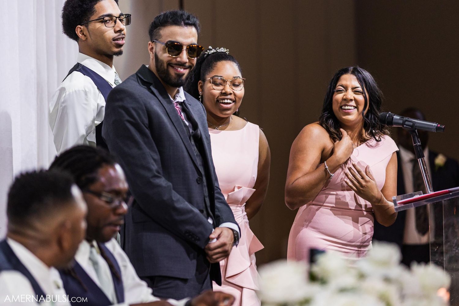 Wedding reception guests share joyful moment during speeches at formal celebration.