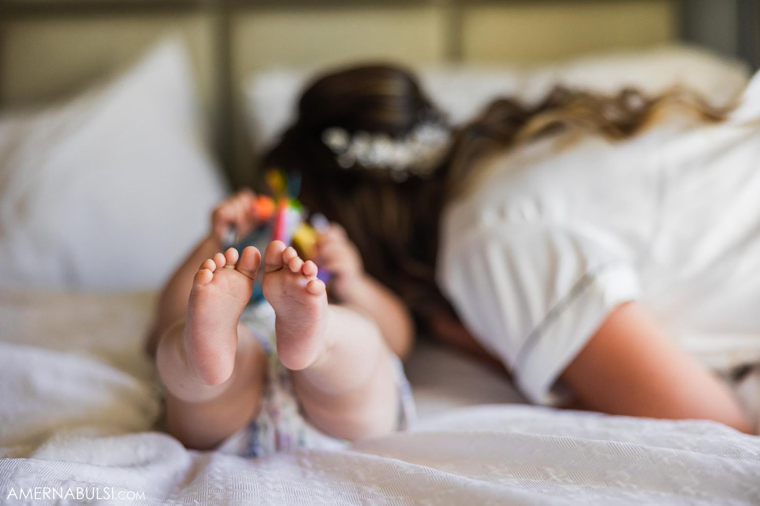 Bare feet with colorful toe decorations shown against white bedding.