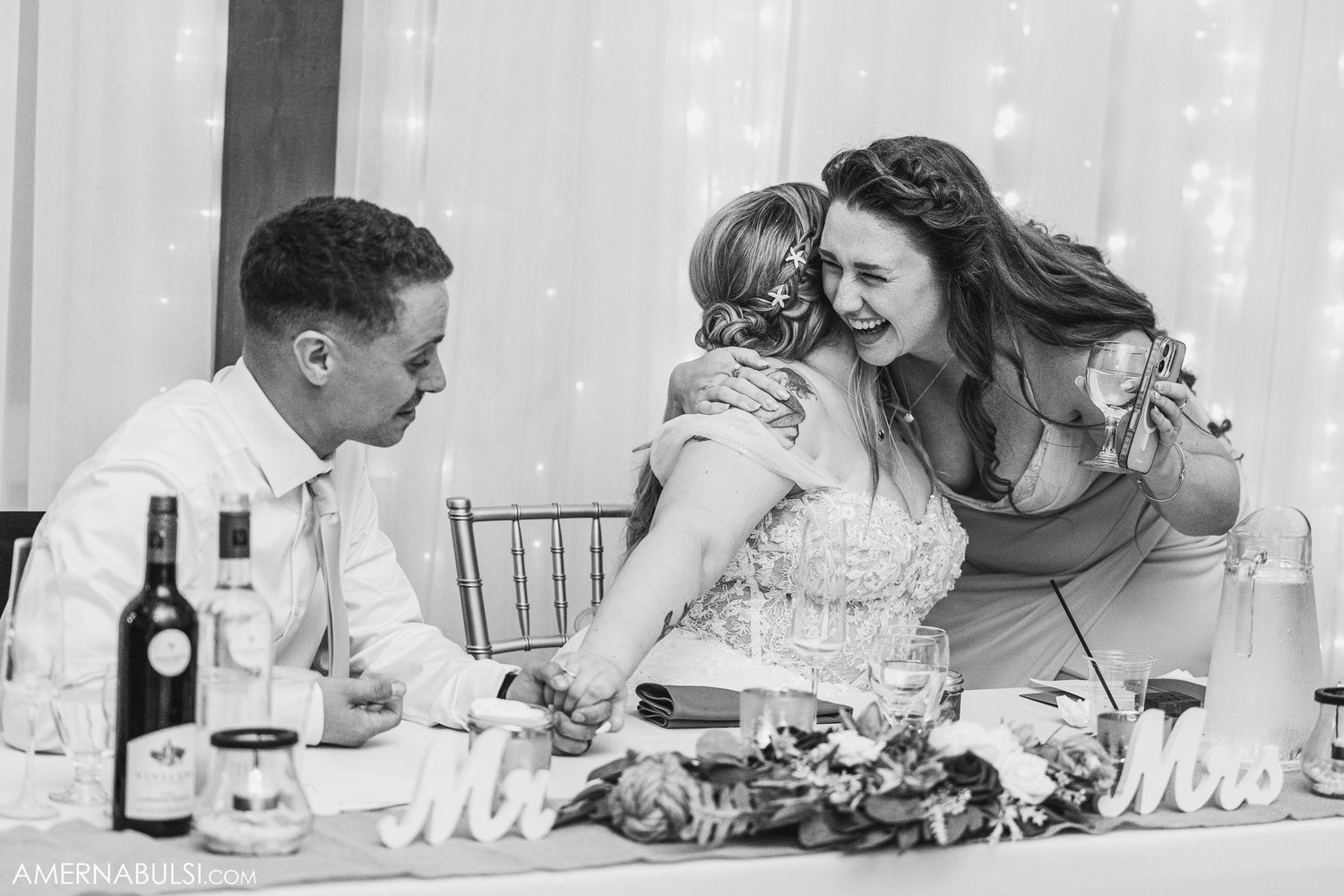 Black and white panoramic shot of wedding guests dining at elegantly set tables.