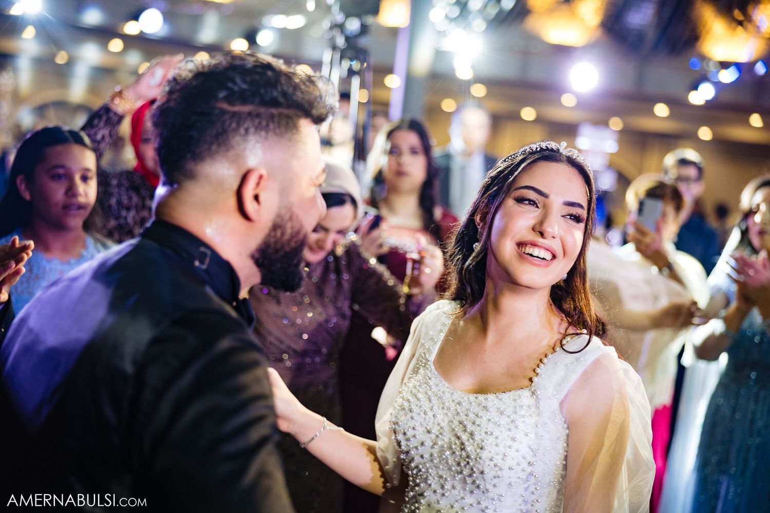 Wedding reception celebration with guests dancing and enjoying the festivities under ambient lighting.