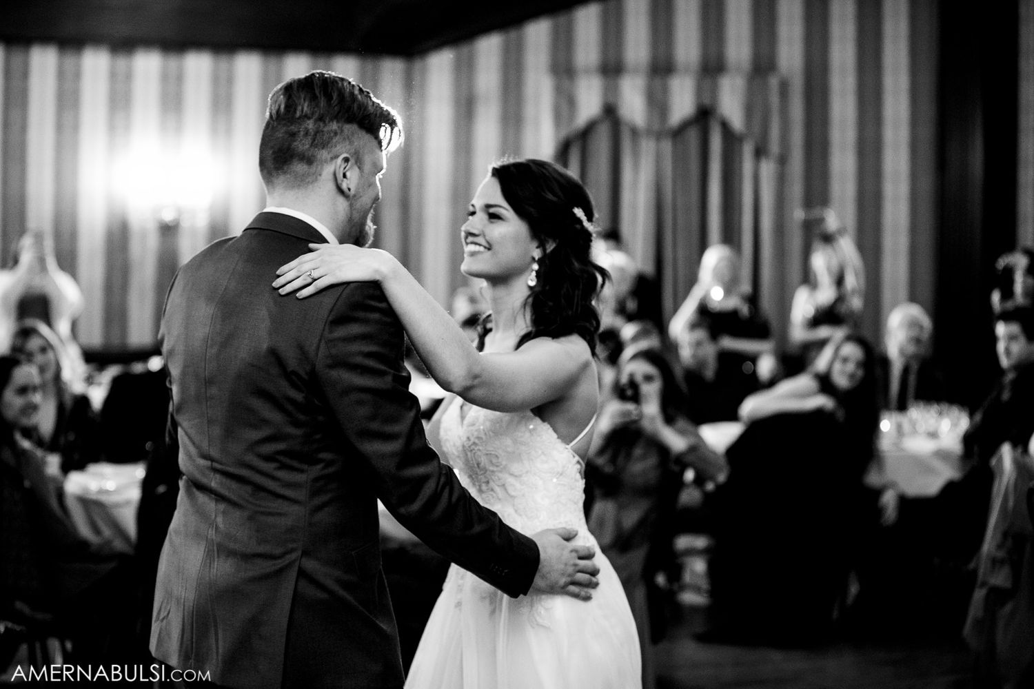 Wedding reception venue with elegant lighting and guests dancing on the dance floor.