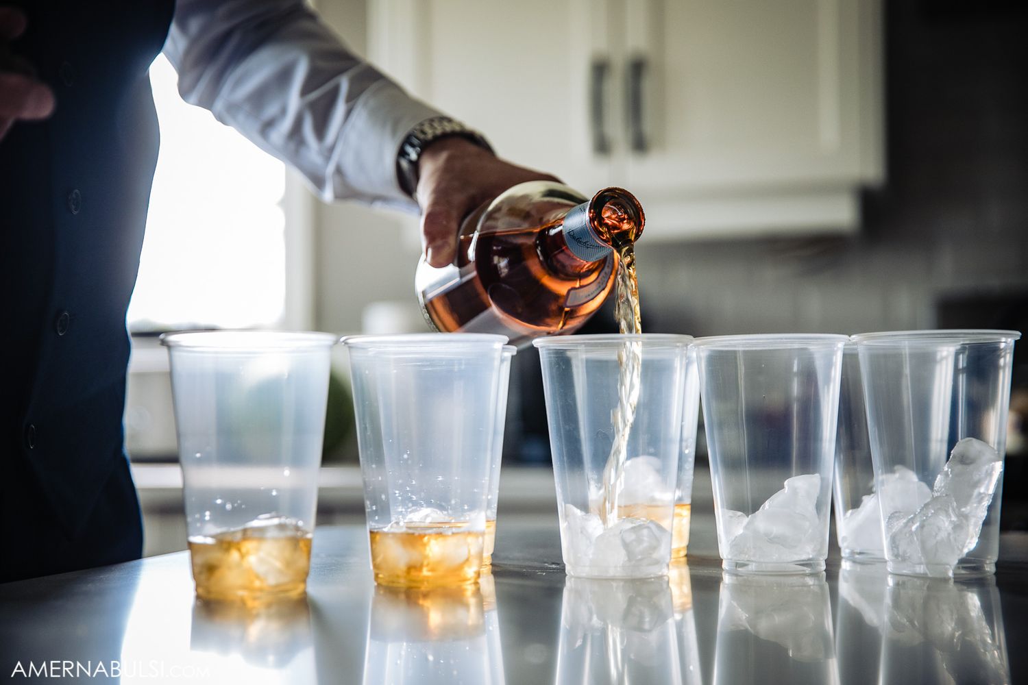 Row of elegant cocktail glasses lined up on counter with amber-colored drinks.