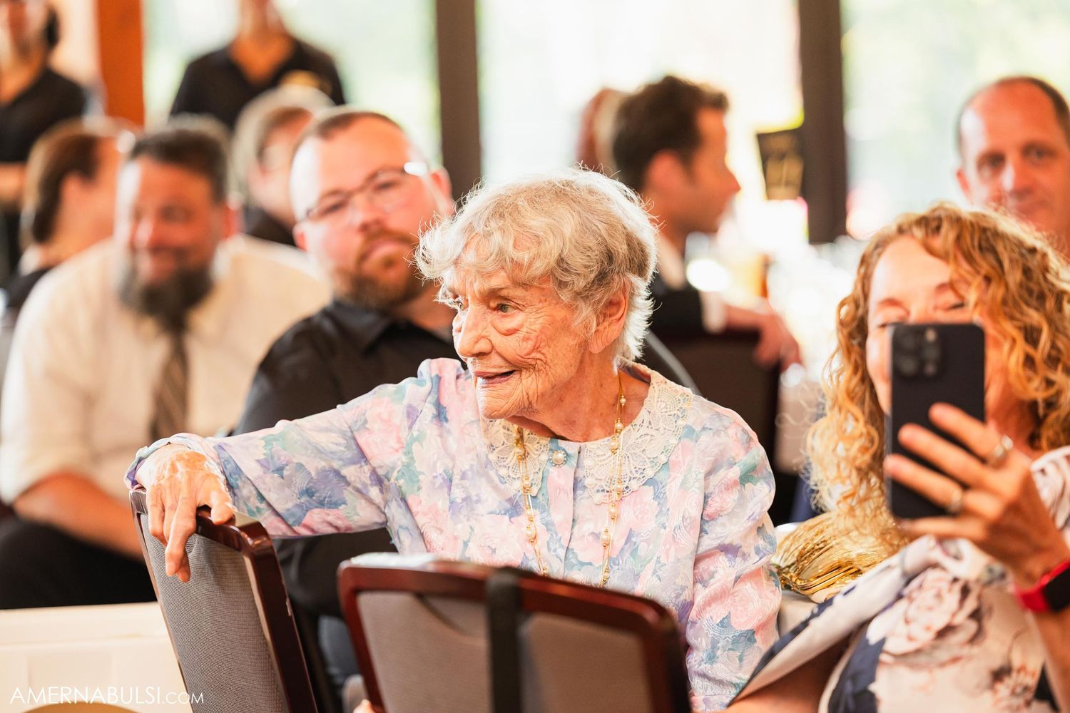 Wedding guests enjoying celebration in bright reception venue.