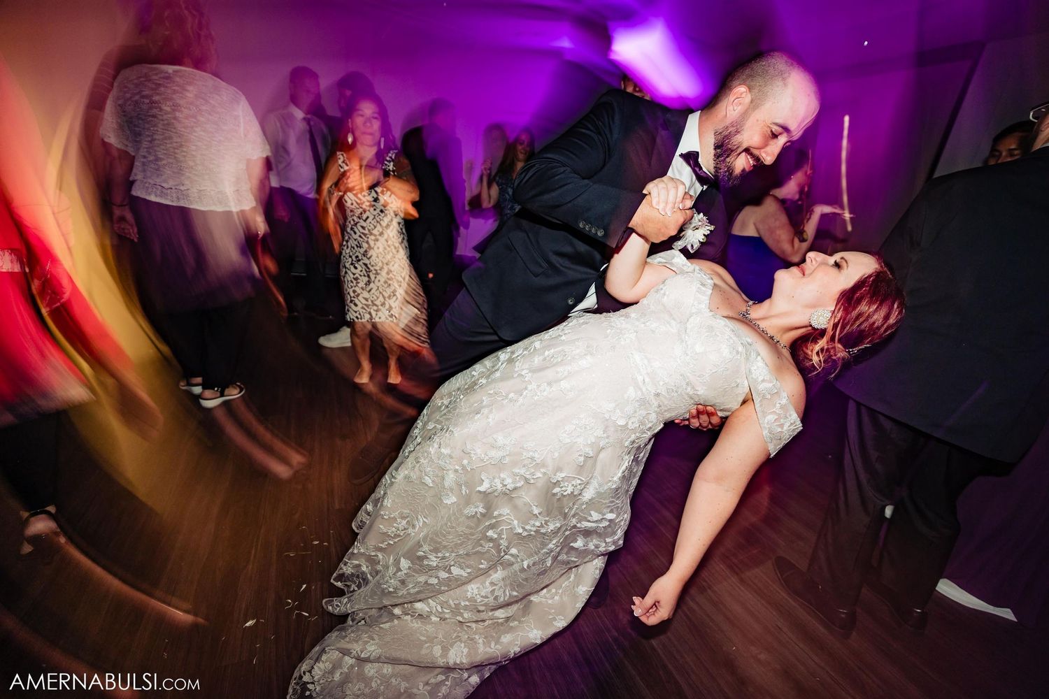 Dynamic dance floor moment at wedding reception with dramatic lighting.
