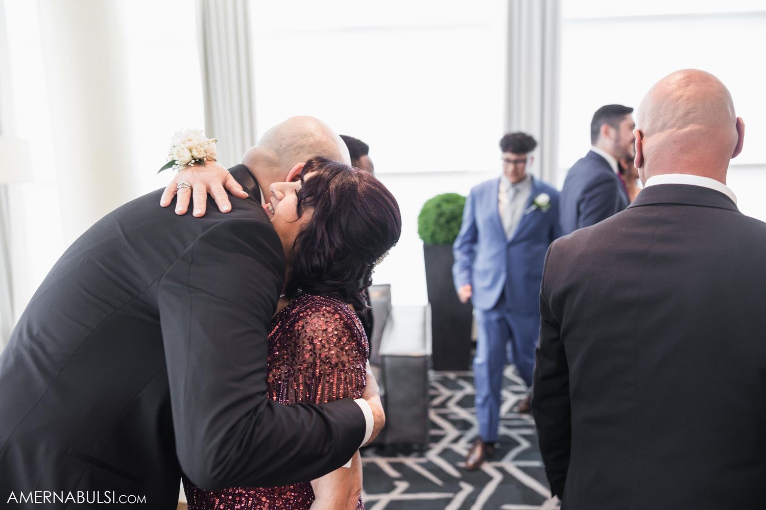 Intimate embrace shared between wedding attendees in formal attire.