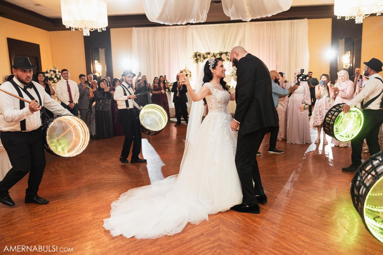 A couple dancing while musicians with drums perform during an indoor wedding reception.