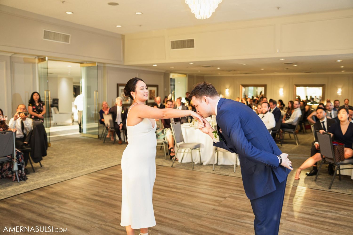 A couple performs a playful dance move during their wedding reception.