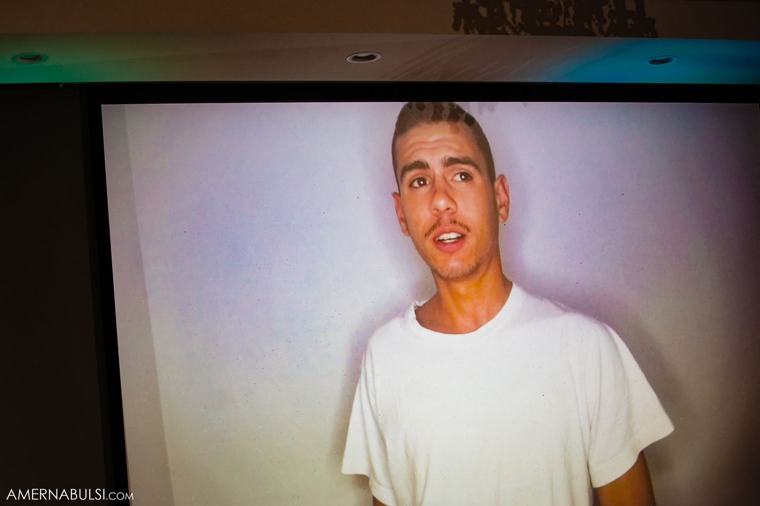 Casual portrait photo displayed on screen showing person in white t-shirt.
