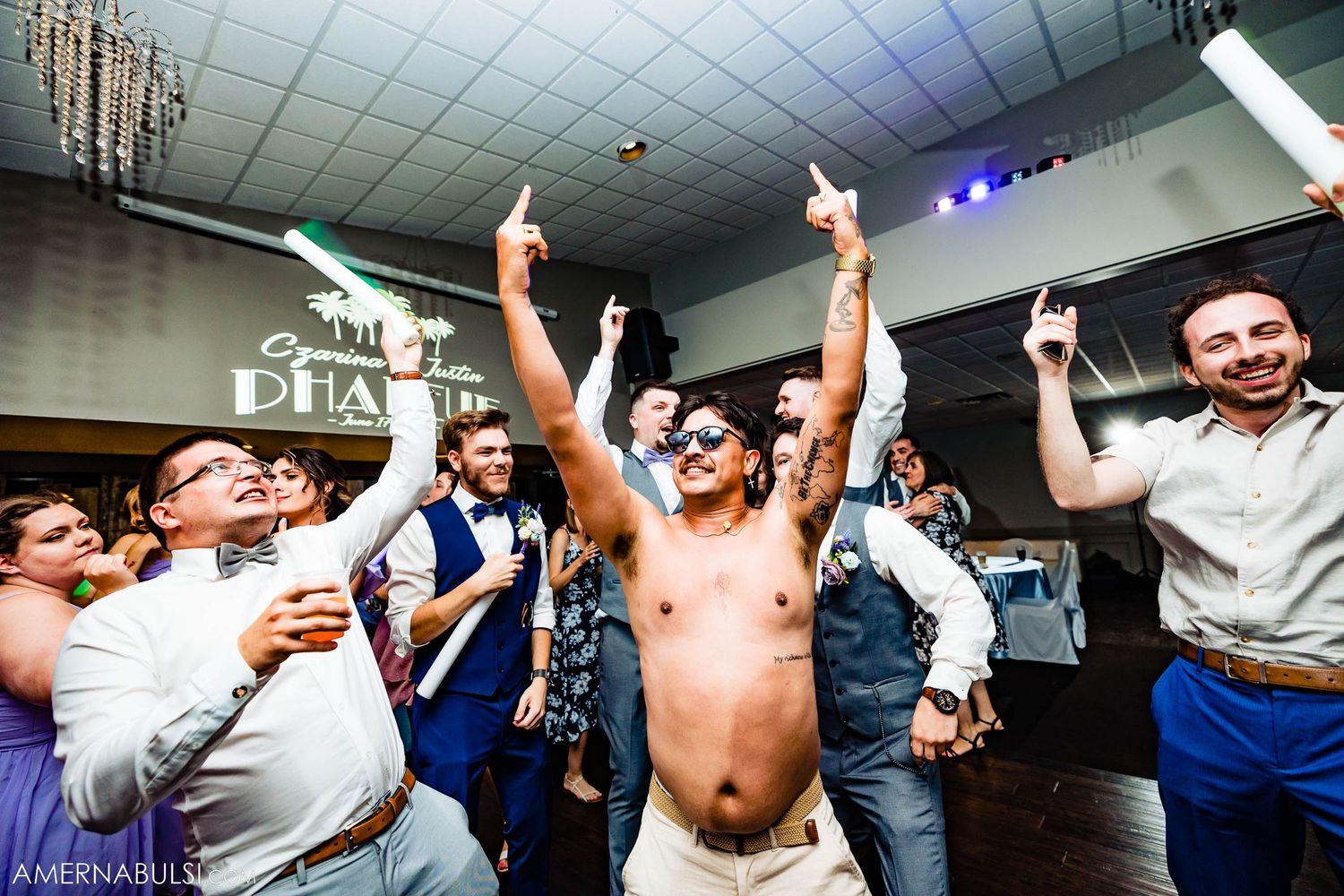 Enthusiastic party guests celebrating with raised arms on crowded dance floor.