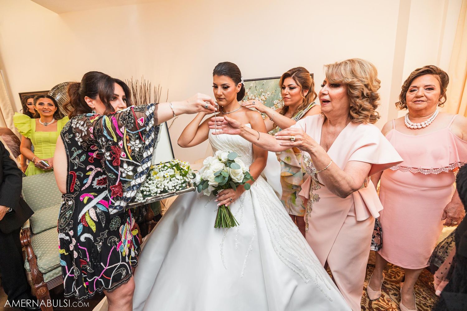 Energetic group reaction shot during wedding preparations with bride in white gown.