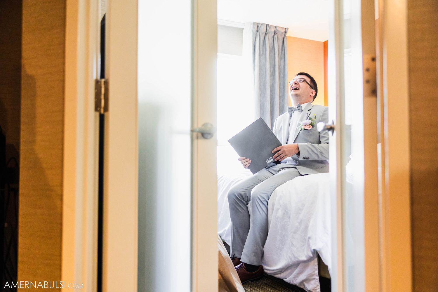 Side view of person in formal wear reading documents while seated on hotel bed.