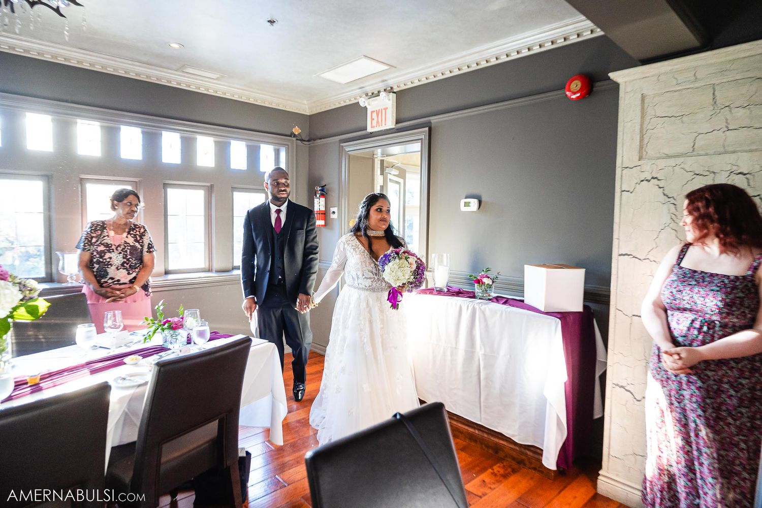 A wedding reception entrance into an elegant room with hardwood floors and natural lighting.