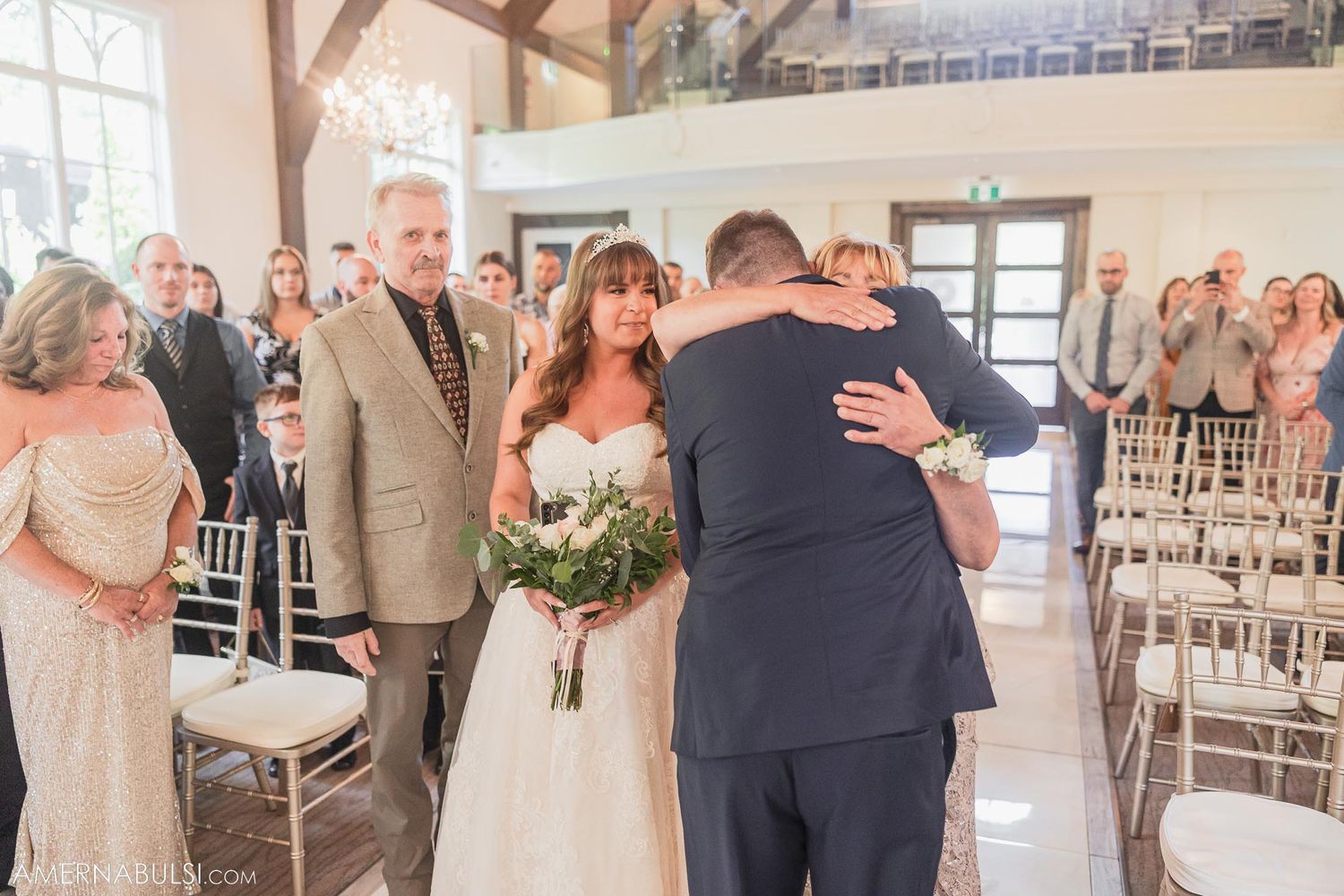 Emotional moment during wedding ceremony in elegant chapel with wooden architectural details.