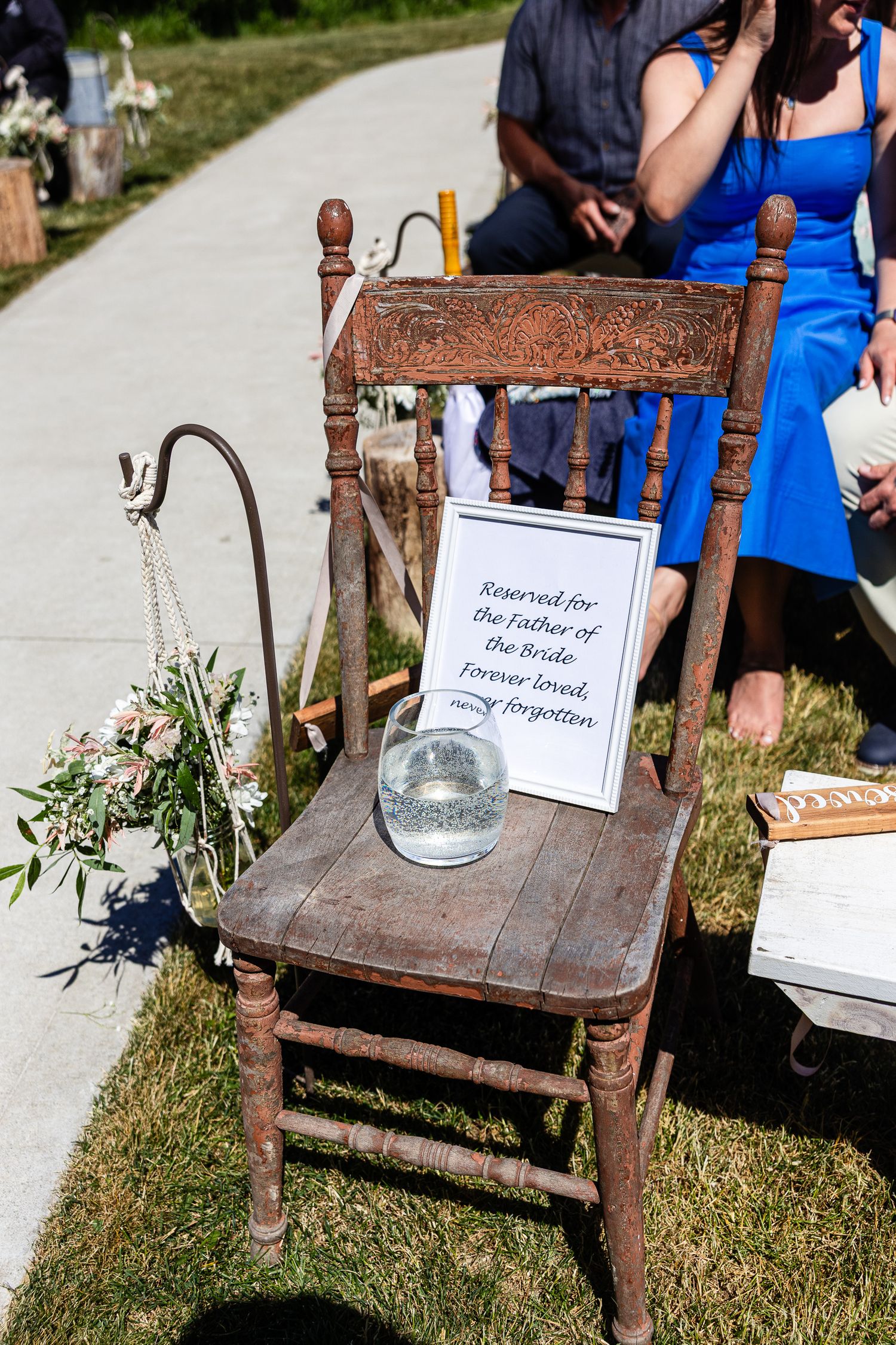 Rustic wooden chair with a reserved sign for the father of the bride and a snow globe at an outdoor wedding.