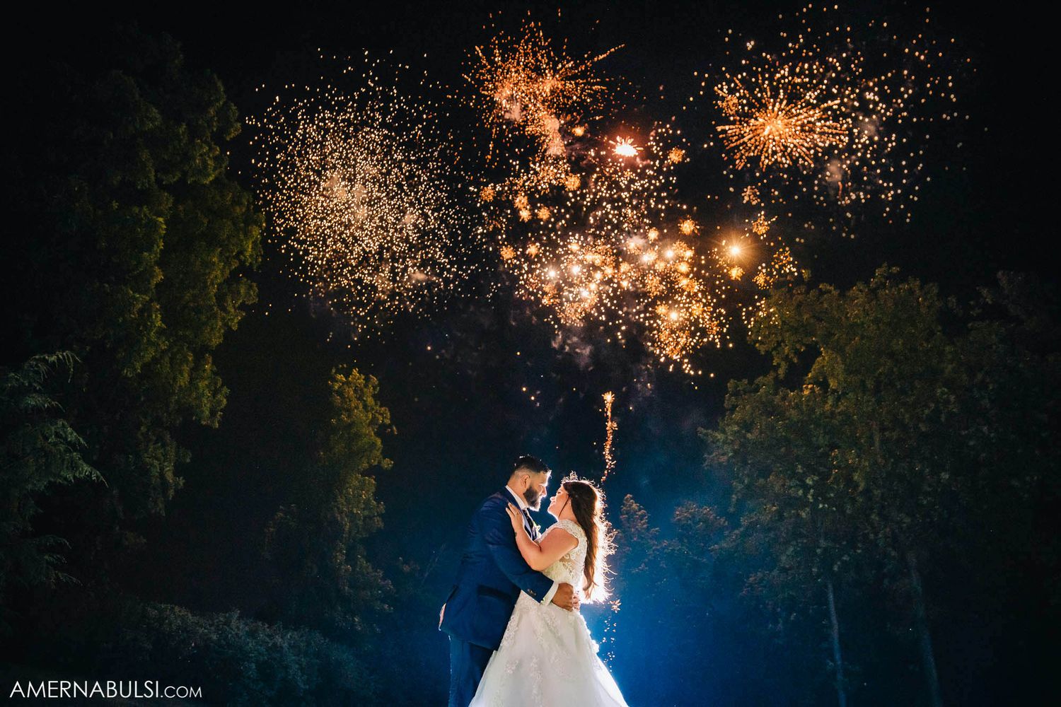 Wedding couple dances under sparklers creating magical nighttime effect.