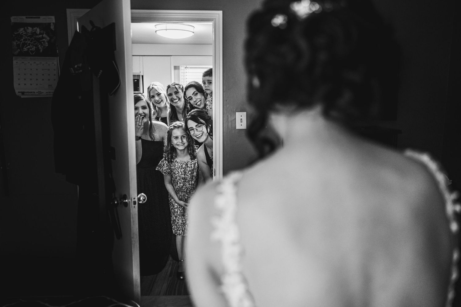 Black and white wedding preparation photos showing emotional moments through doorways.